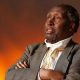 Ngũgĩ wa Thiong’o, Kenyan author, literary giant, African language advocate, photographed at a book event, known for Weep Not, Child, Devil on the Cross, exiled writer, freedom of expression, anti-colonial voice. Image shows Ngũgĩ later in life, seated with books, calm expression, representing decades of African literature, resistance, and storytelling. A major influence on African writers, celebrated across the continent, remembered for promoting Kikuyu language in fiction, and challenging both colonial and post-independence oppression. Suitable for articles on African literature, pan-African identity, cultural icons, author tributes, and modern African history, Joburg ETC