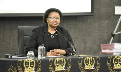 Pretoria courtroom exterior, South African Hawks police logo, International Pentecost Holiness Church crest, courtroom judge gavel closeup, protestors outside High Court Pretoria, Joburg ETC