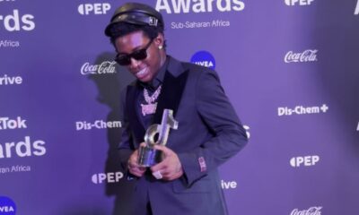 Shallipopi standing on red carpet at 2025 TikTok Awards Africa, crowd cameras flashing; Nigerian singer Shallipopi performing live on stage under colourful lights, vibrant energy; Fans celebrating in club dancing to Afrobeats, hands up silhouette crowd, Portrait of Nigerian musician Shallipopi in casual streetwear, neutral background; Johannesburg skyline night view city lights, South Africa urban metropolis; TikTok Awards 2025 stage lights and audience cheering, continental music event energy Joburg ETC